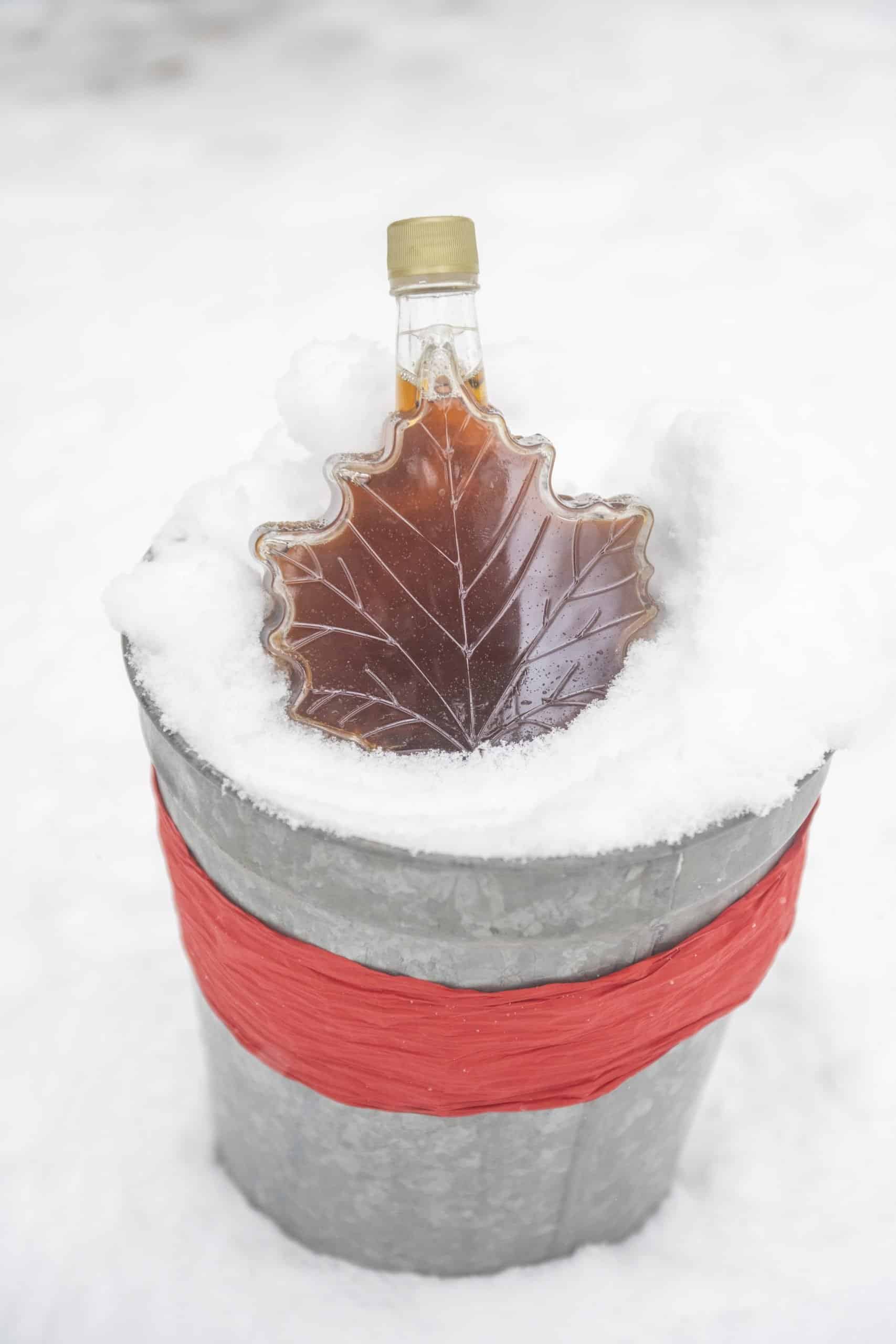 Maple Leaf Shaped bottle filled with maple syrup in the snow