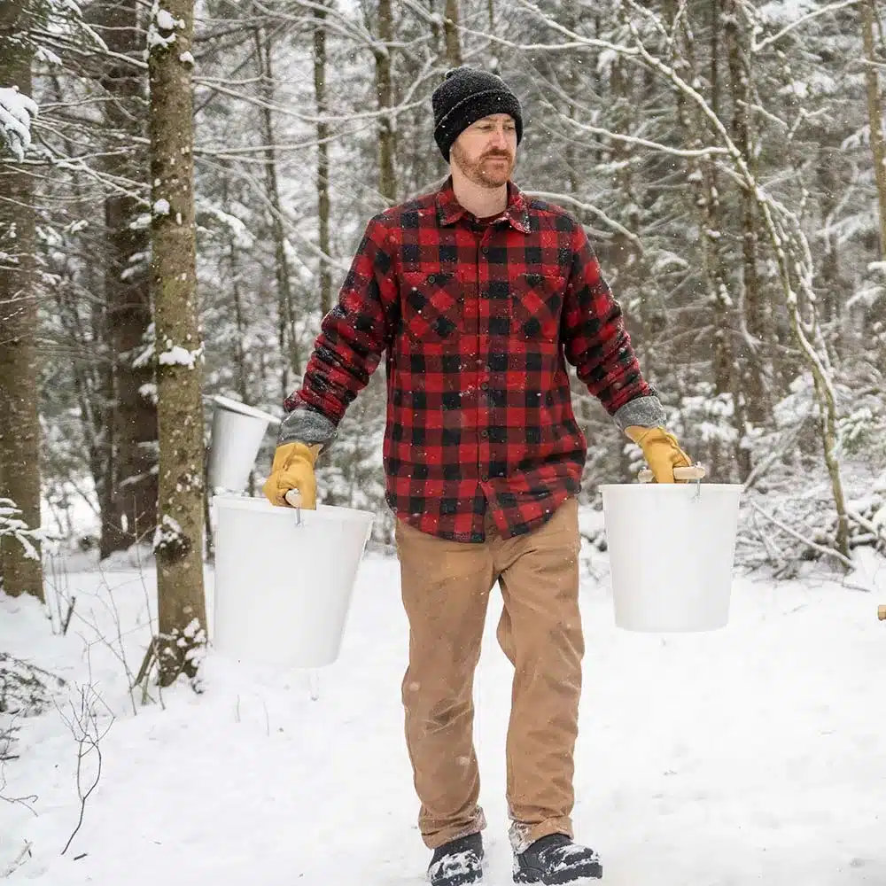 person carrying maple sap buckets