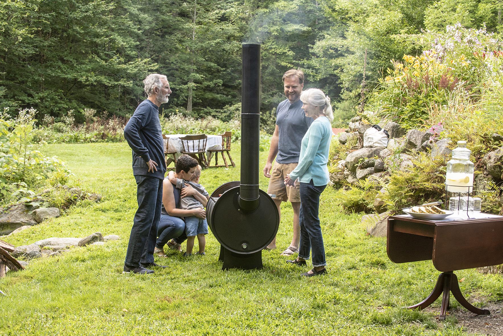 A family standing around a grill, looking happy.