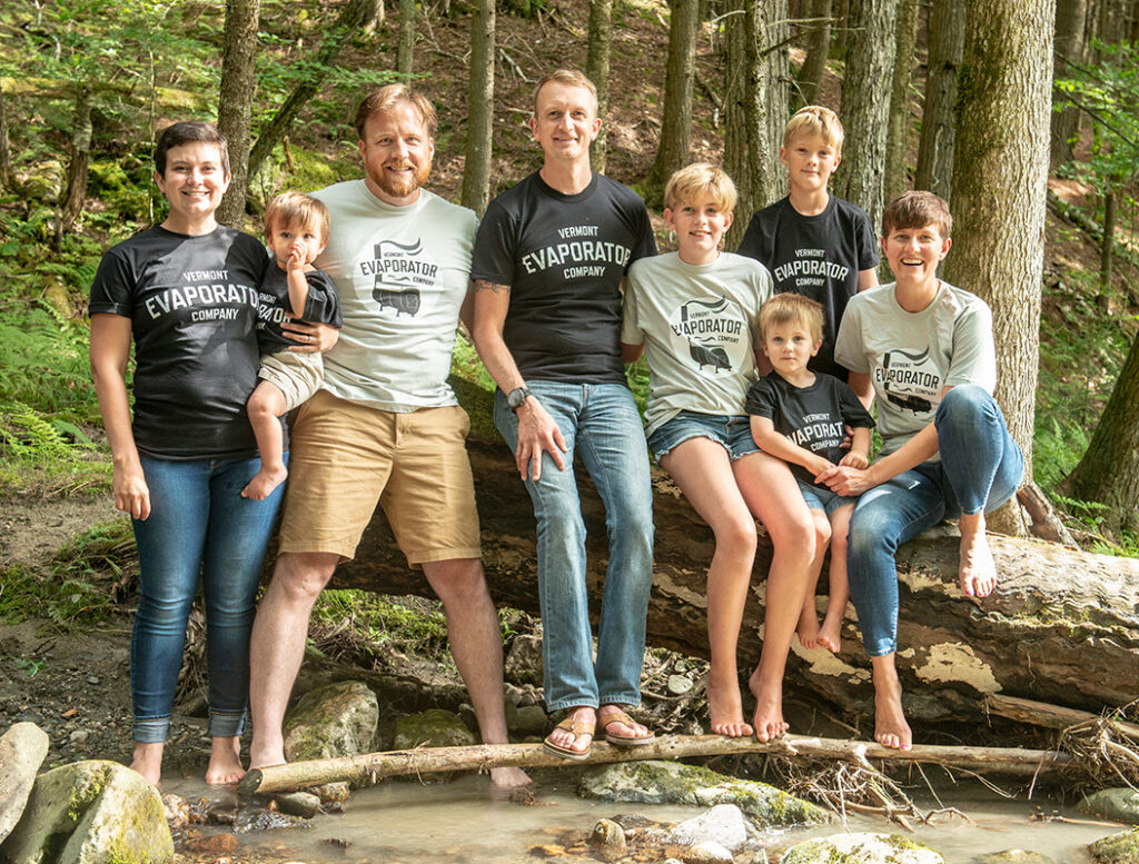 a family sitting on a log in a river with matching t-shirts